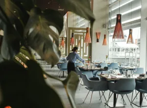 woman in front on brown dining table and chairs inside building